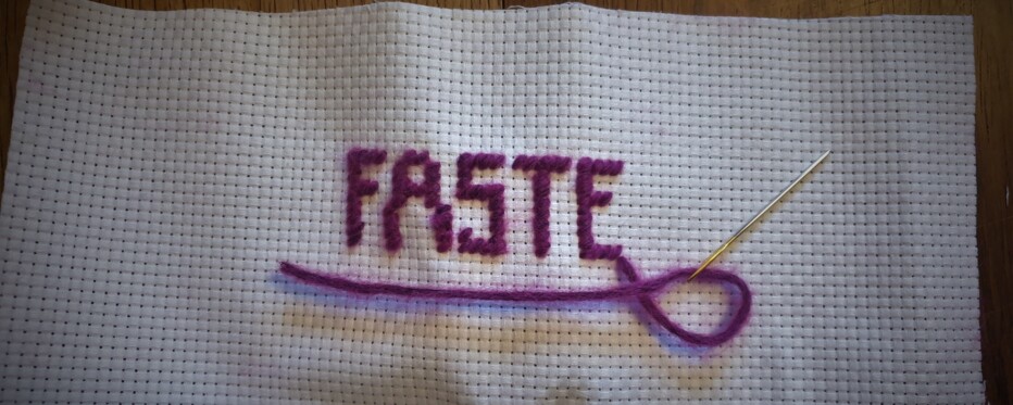 Ordet FASTES skrevet med broderi