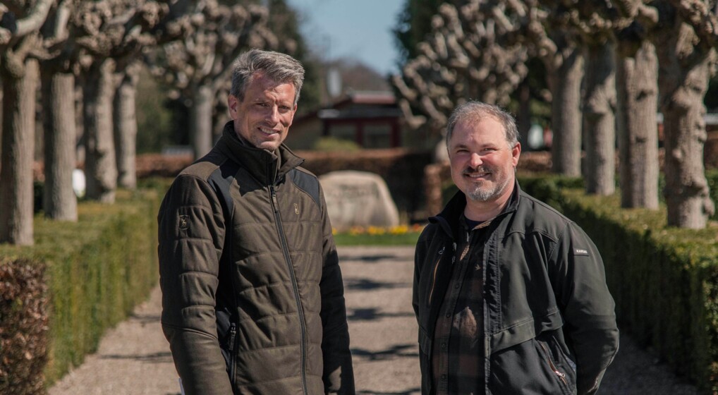 Kirkegårdsleder Dennis Andersen, t.v., og kirkegårdsgartner Allan Holm står her foran en allé af knudebeskårne lindetræer. Dennis Andersen og Allan Holm